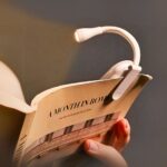 Mini lampe LED de lecture avec pince Mini lampe LED de lecture avec pince, de couleur blanche, sur un livre.