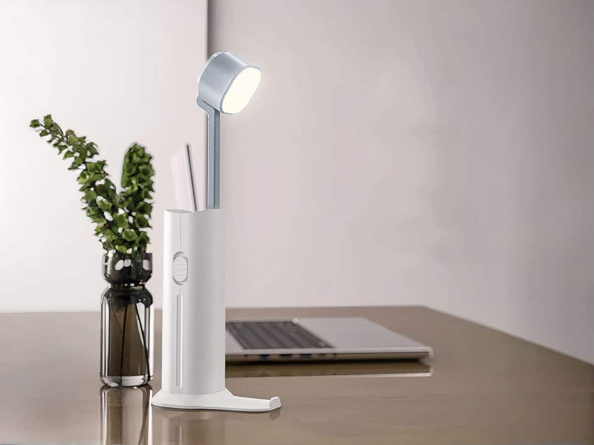 Mini lampe LED design avec son support de transport Mini lampe LED design avec son support de transport, sur un bureau à côté d'un ordinateur.