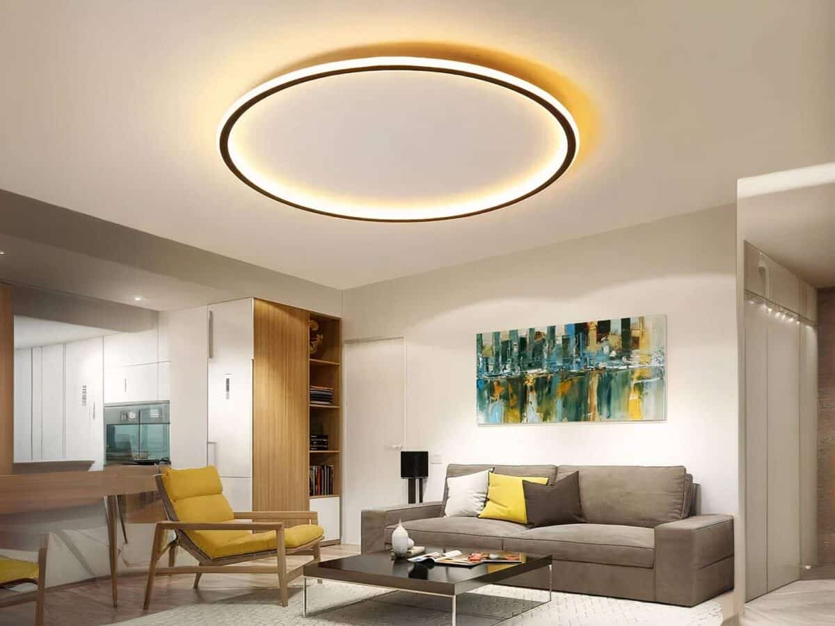 Plafonnier LED aluminium noir circulaire Plafonnier LED aluminium noir circulaire installé au plafond d'un salon avec un canapé gris et un fauteuil jaune, ainsi qu'une table basse carrée noire.