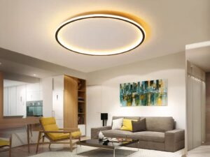 Plafonnier LED aluminium noir circulaire installé au plafond d'un salon avec un canapé gris et un fauteuil jaune, ainsi qu'une table basse carrée noire.