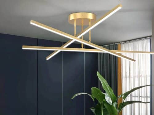 Plafonnier LED minimaliste moderne doré, trois bâtons qui s'entrent-croise. Installé sur un plafond gris clair.