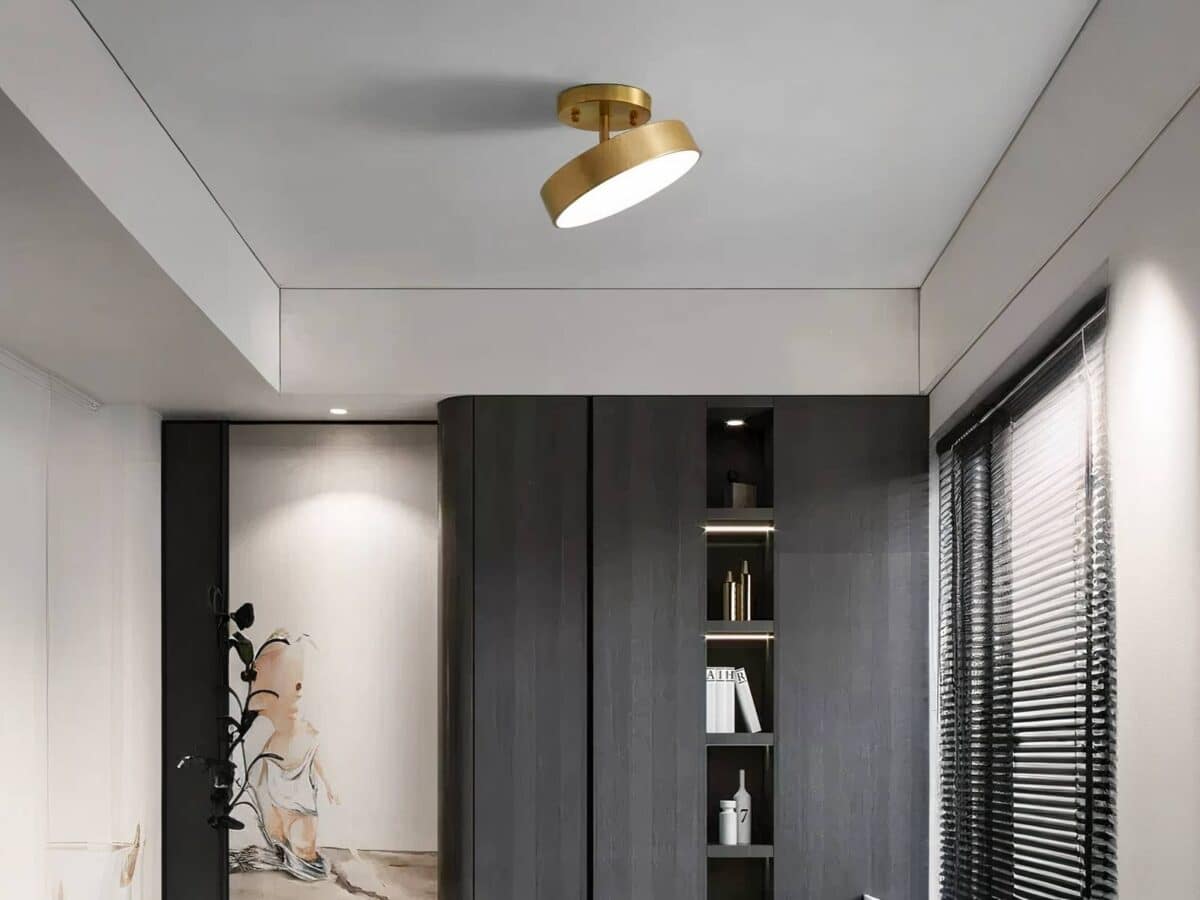 Plafonnier LED nordique métal rond doré Plafonnier LED nordique rond doré, installé sur un plafond gris, dans une pièce de vie. Il est orienté vers la droite et allumé.