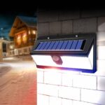 Projecteur extérieur LED solaire détecteur de mouvement Projecteur extérieur LED solaire avec détecteur de mouvement allumé et installé sur un mur de briques blanches.