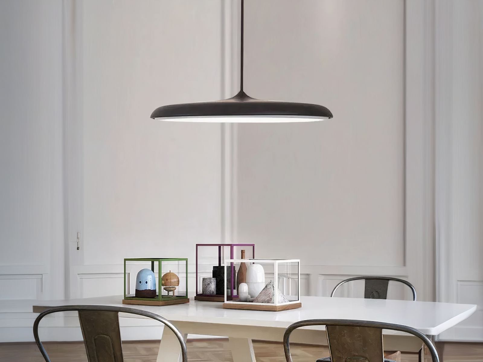 Suspension LED design en forme de soucoupe noire, au dessus d'une table de salle à manger.