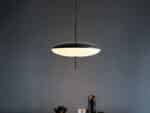 Suspension LED design minimaliste noire et blanche, dans une pièce sombre.