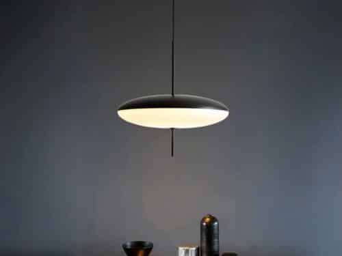 Suspension LED design minimaliste noire et blanche, dans une pièce sombre.
