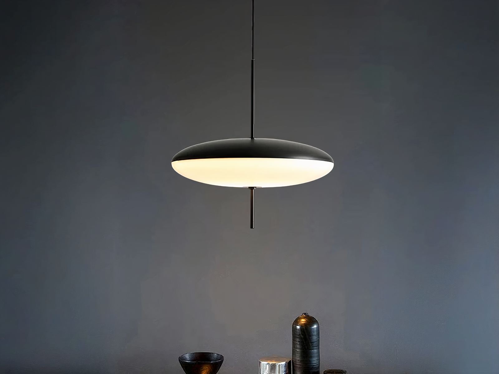 Suspension LED design minimaliste noire et blanche, dans une pièce sombre.