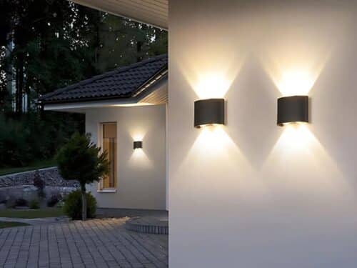 Deux lampes LED rectangulaires fixées à un mur extérieur, dans un jardin.