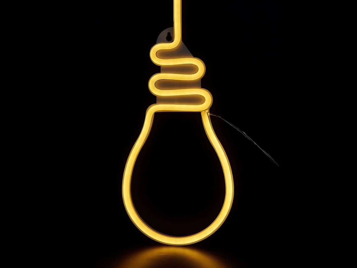 IMG_0924_ENSEIGNE_ NEON_LED_AMPOULE A ACCROCHER_01 Une enseigne lumineuse en forme d'ampoule, en néon LED et silicone. Elle brille sur un fond noir