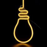 Enseigne ampoule néon LED et silicone à accrocher Une enseigne lumineuse en forme d'ampoule, en néon LED et silicone. Elle brille sur un fond noir