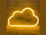 Enseigne nuage néon LED en silicone de couleur jaune, accrochée sur un mur texturé, illuminant la pièce d’une lumière douce et chaleureuse, câblage USB visible.