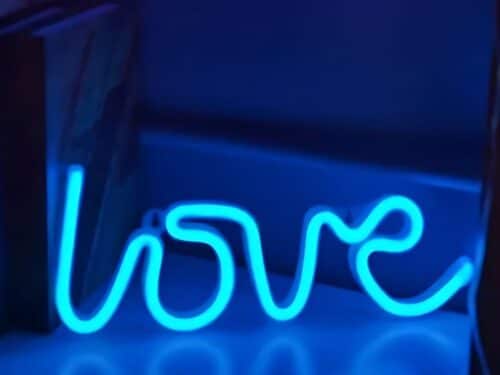 Enseigne lumineuse de couleur bleue qui éclaire une étagère en formant un halo de lumière bleue assez conséquent.