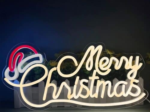 Une enseigne lumineuse néon LED représentant Merry Christmas sur deux lignes. La lettre C de christmas est surmonté d'un chapeau de père noël lumineux blanc et rouge.