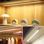 Photos de 3 possibilités d'utilisation d'une réglette lumineuse LED avec détecteur infrarouge. La photo supérieure montre la réglette installée en dessous d'une étagère de bibliothèque pour mettre en valeur les bibelots qui y sont exposés, la deuxième photo montre une réglette dans une penderie et la troisième montre la réglette sous un meuble haut de cuisine, éclairant sans doute un plan de travail.