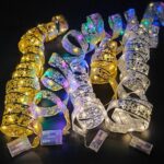 Cinq rubans lumineux LEd pour décorer le sapin de Noël ouverts en serpentins sur un fond noir.