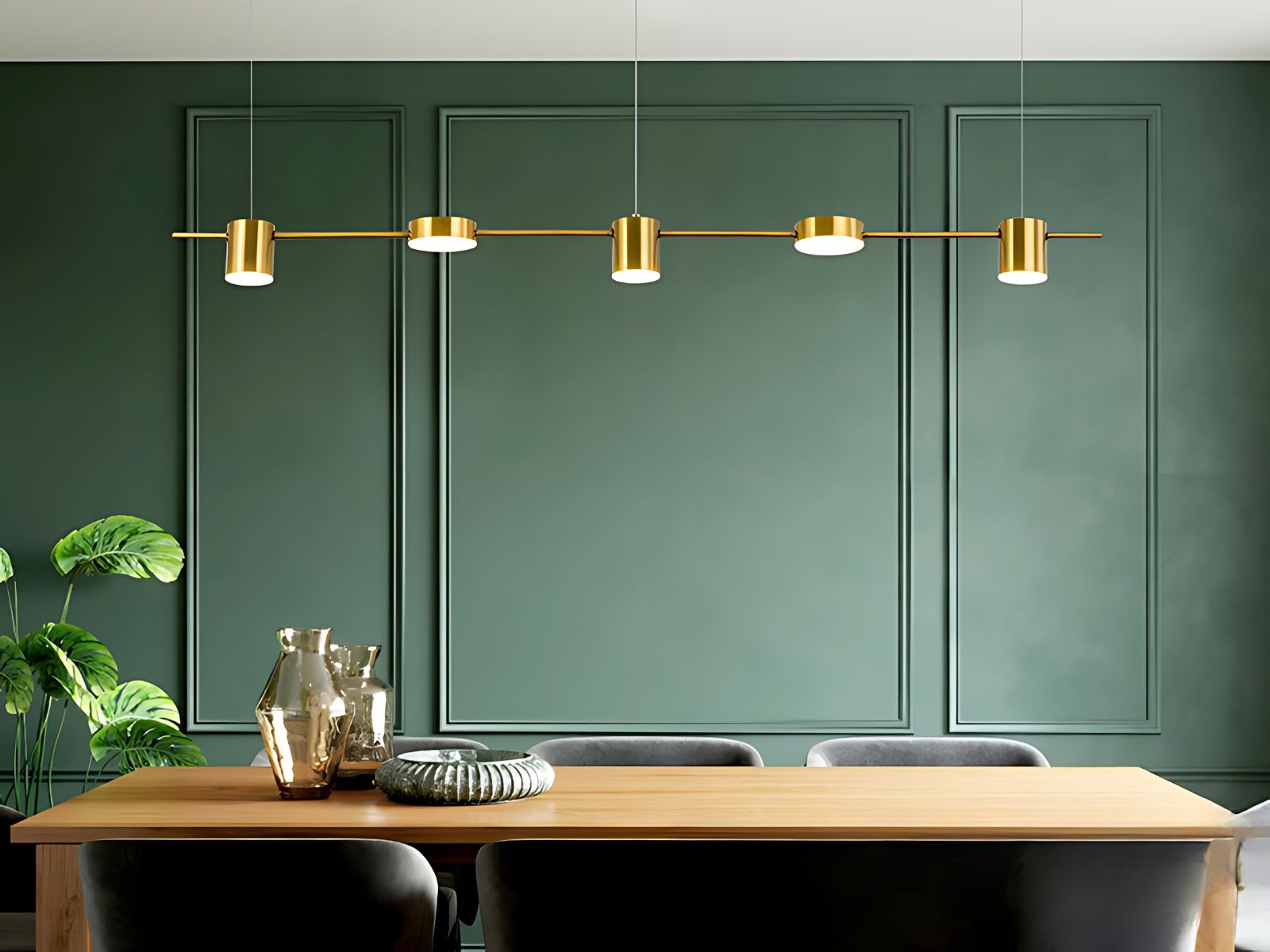 Le lustre à led doré au design moderne au-dessus d'une table de salle à manger en bois au fond un mur vert