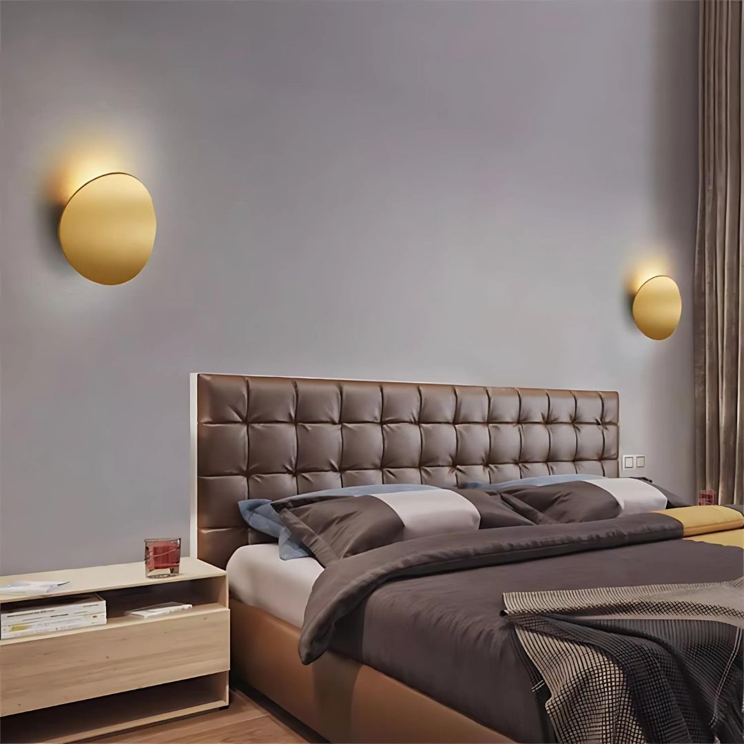 Applique murale en aluminium moderne Les deux appliques murales en aluminium en doré de chaque côté d'un lit sur un mur taupe.