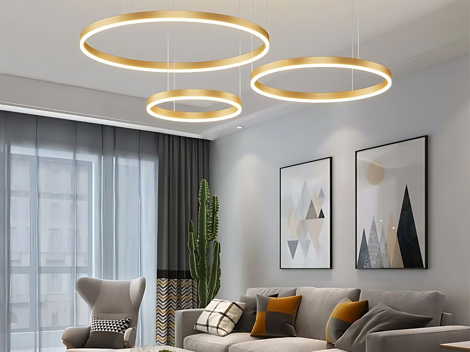 Le lustre LED suspendu moderne à trois anneaux dans un salon avec deux tableaux sur le mur , une grande baie vitrée avec un rideau gris.