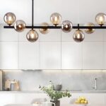 Lustre suspendu en verre au style contemporain Le lustre suspension en verre au style contemporain dans une cuisine au dessus d'une grande table blanche dessus avec une plante verte et un saladier avec des citrons jaunes