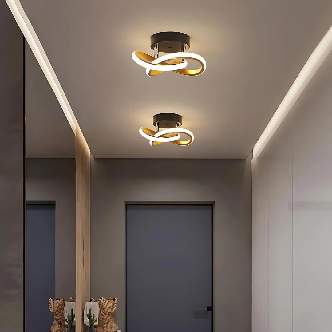 Plafonnier à bandes LED entrelacées Le plafonnier à bande à LED entrelacées dans un couloir peint en taupe avec une porte noire.