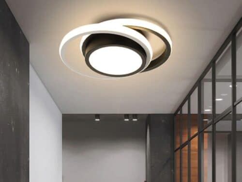 Le plafonnier à LED suspendu avec avec anneaux ronds au design moderne dans un couloir gris avec sur le mur droit une verrière.
