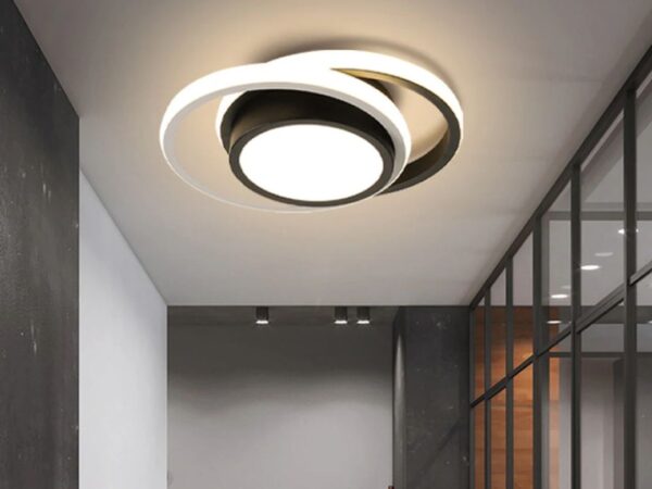 Le plafonnier à LED suspendu avec avec anneaux ronds au design moderne dans un couloir gris avec sur le mur droit une verrière.