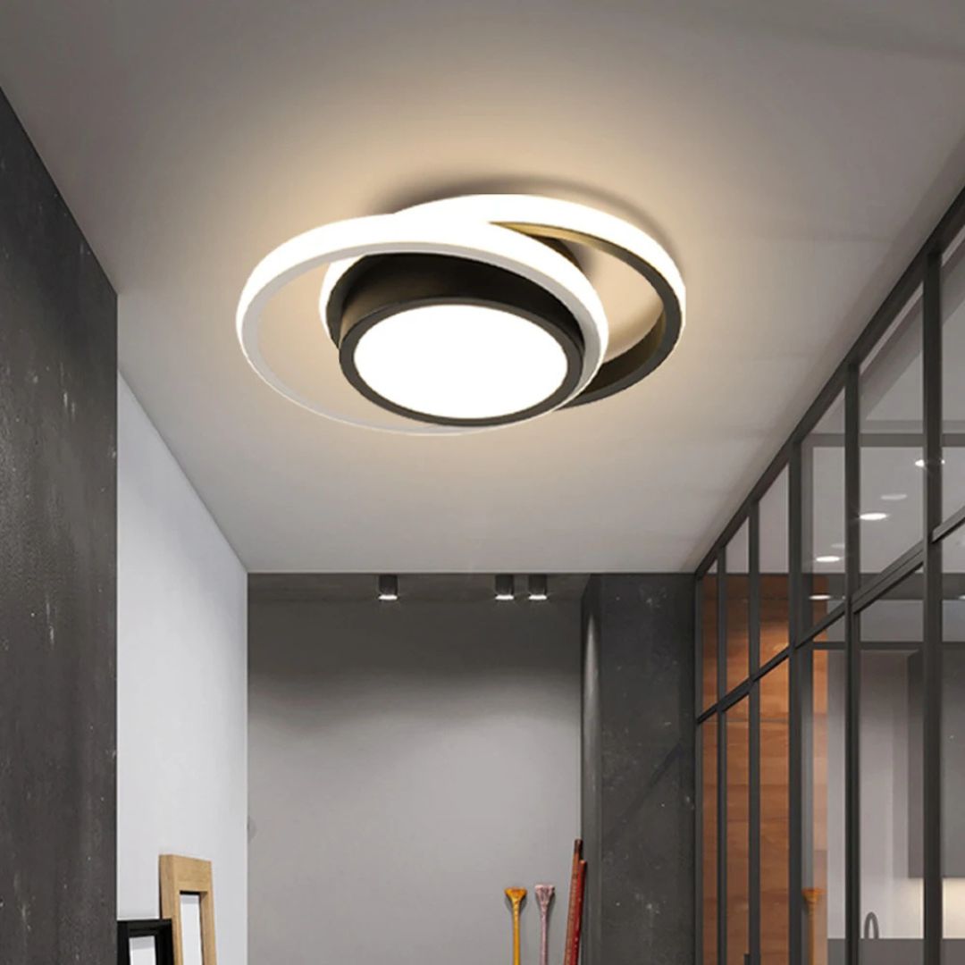 Le plafonnier à LED suspendu avec avec anneaux ronds au design moderne dans un couloir gris avec sur le mur droit une verrière.