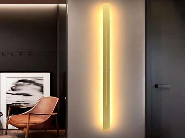 L'applique murale LED pour salon est installée sur un mur blanc où se trouve un fauteuil couleur rouille devant une toile noire et blanche.