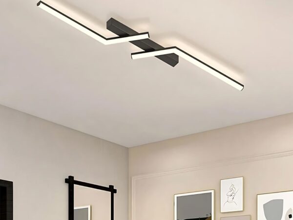 Le plafonnier à LED décoratif à lignes asymétriques sur un plafond blanc. plusieurs cadres sont présents sur les murs.
