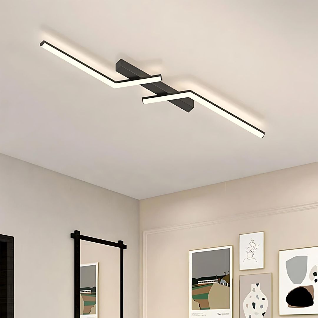 Plafonnier LED décoratif à lignes asymétriques Le plafonnier à LED décoratif à lignes asymétriques sur un plafond blanc. plusieurs cadres sont présents sur les murs.