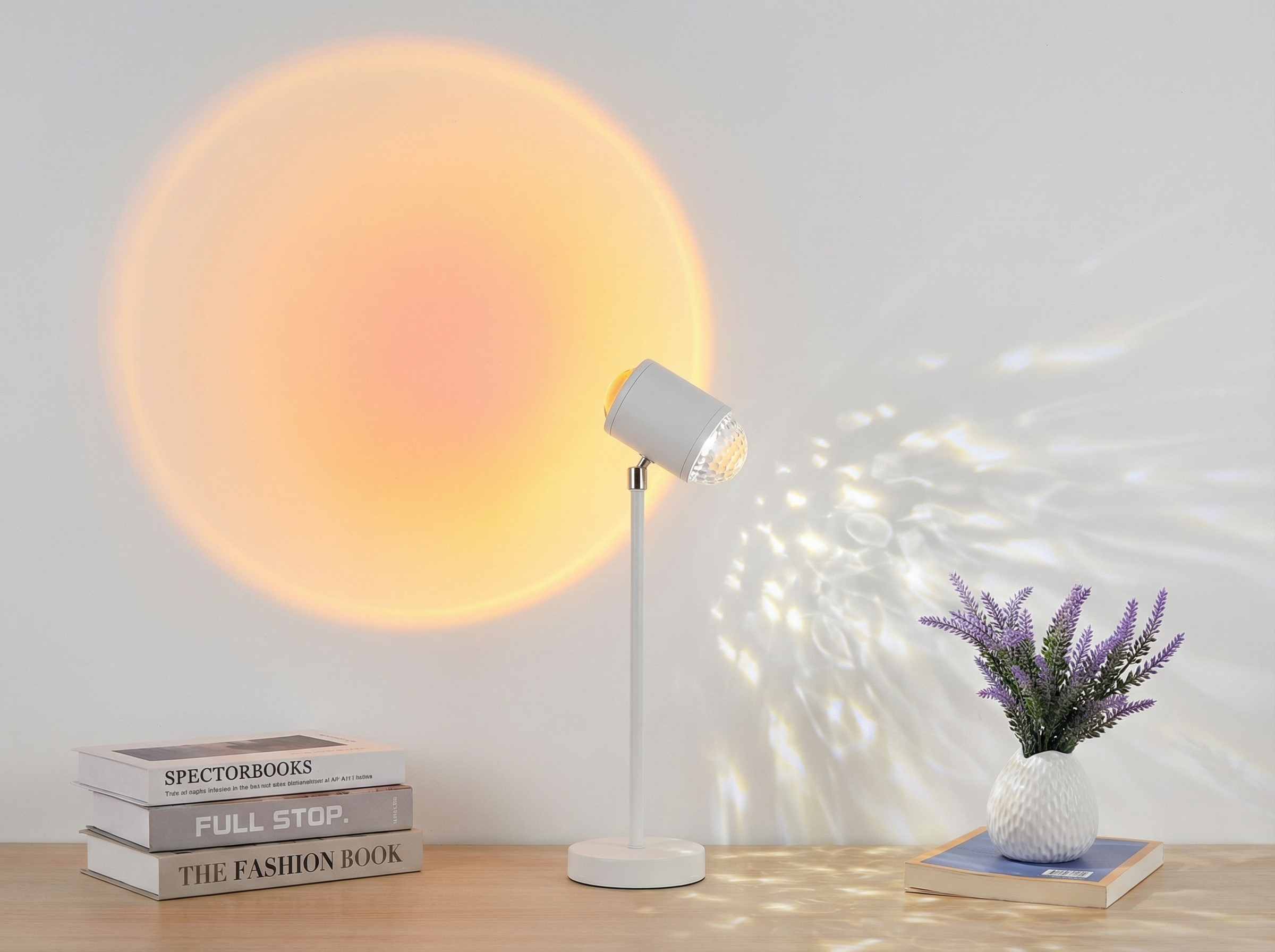 Lampe blanche posée sur un bureau en bois, projetant un cercle lumineux orange sur un mur et des reflets lumineux à droite, près de livres et d’un petit vase de fleurs.