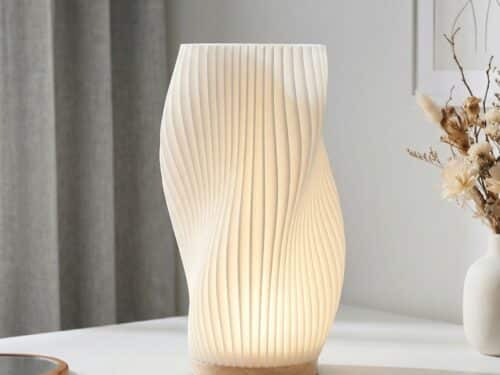 Lampe de table LED dimmable abat-jour plissé avec structure ondulée moderne diffusant lumière douce et réglable, posée sur table.